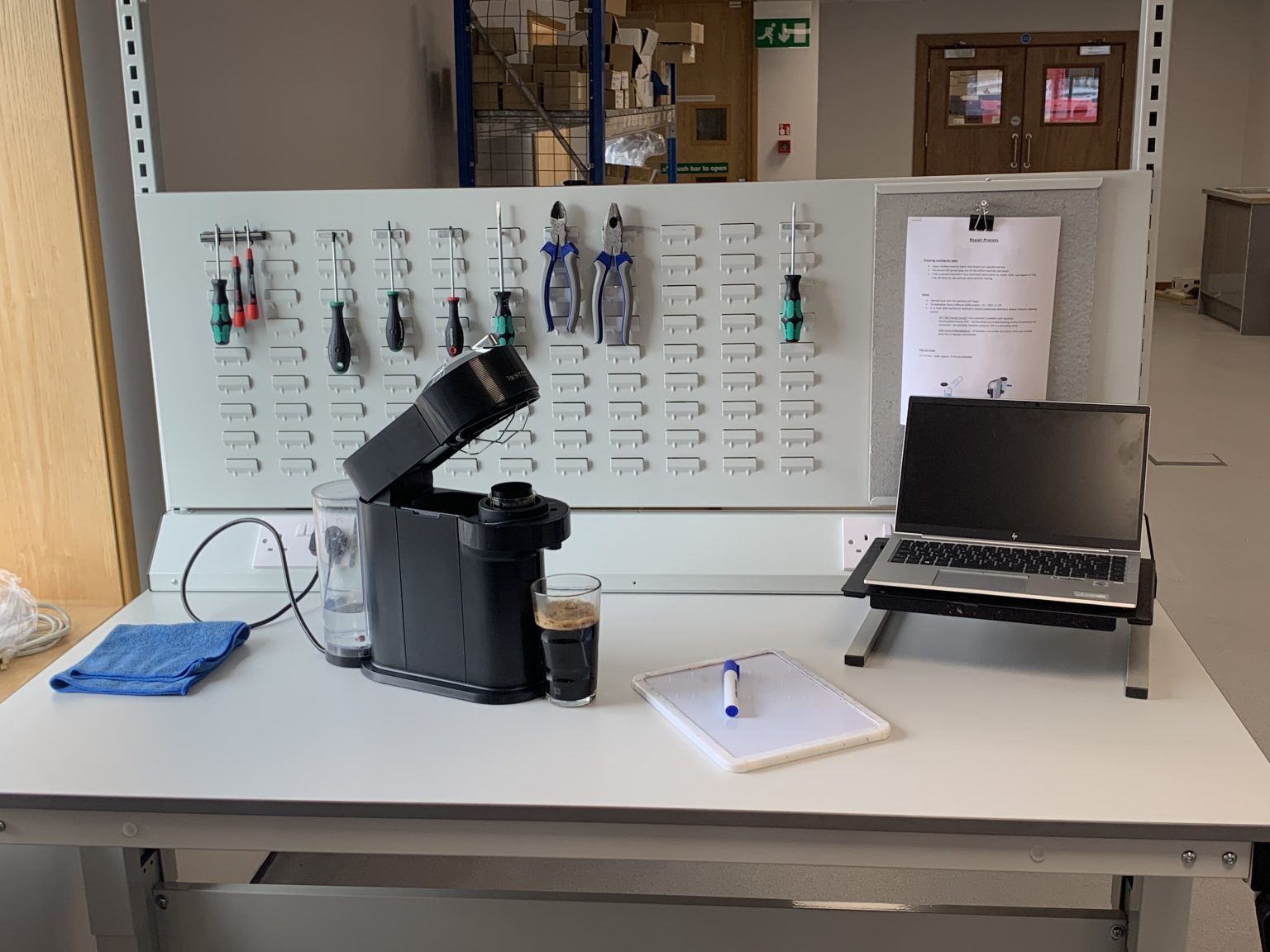 A Nespresso Machine on a repair bench with tools and repair equipment around it.